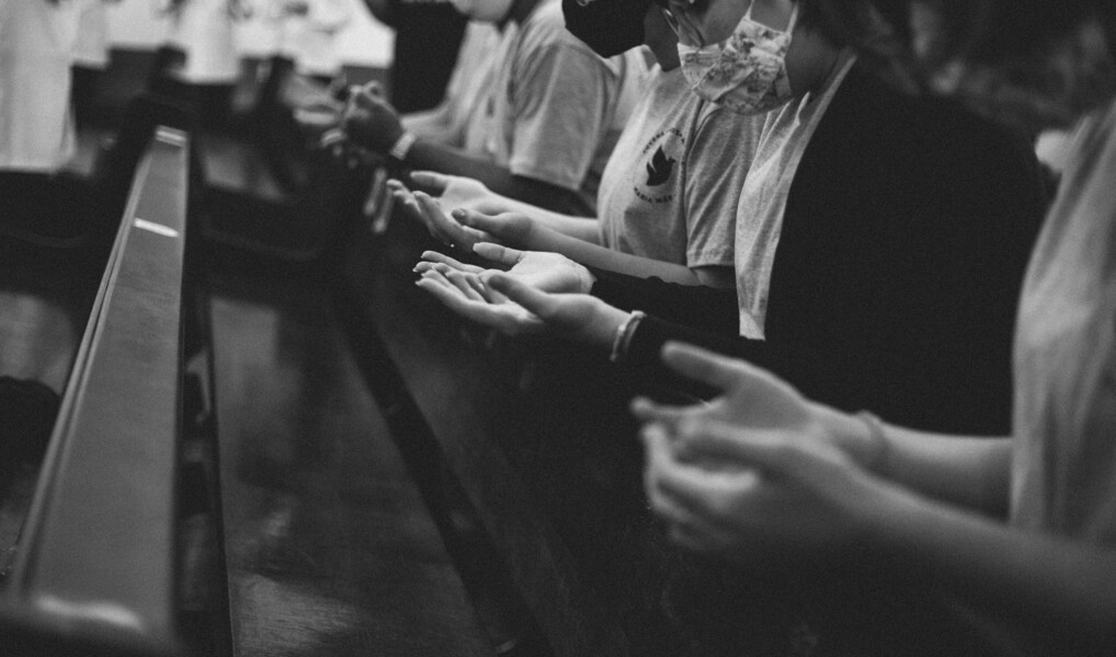 En gruppe mennesker beder eller lovpriser ved en kirkebænk